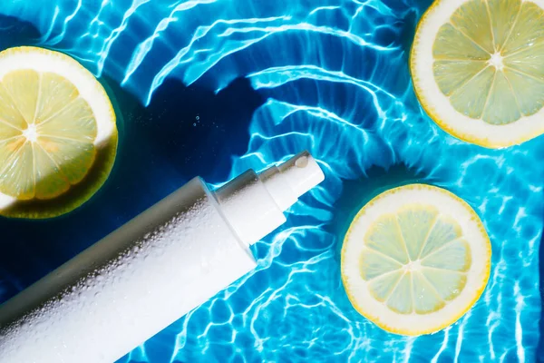 Weißes Schönheitsprodukt Sonnencreme Fläschchen Sprüher in transparentem Süßwasser mit Flecken und Wellen, Zitrusfrüchte. — Stockfoto