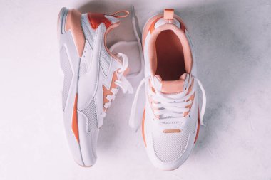 Beyaz kadın spor ayakkabıları, beyaz beton arka planda mercan parçaları var. Üst Manzara. Düz yatıyordu.