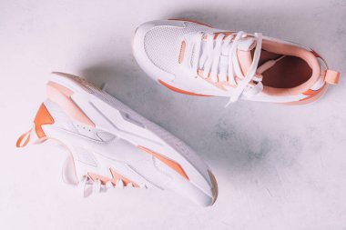 Beyaz kadın spor ayakkabıları, beyaz beton arka planda mercan parçaları var. Üst Manzara. Düz yatıyordu.