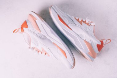 Beyaz kadın spor ayakkabıları, beyaz beton arka planda mercan parçaları var. Üst Manzara. Düz yatıyordu.