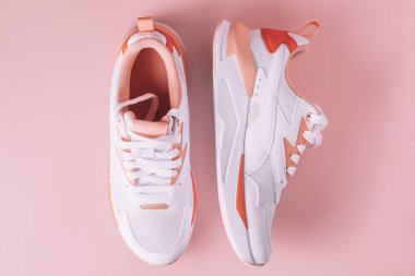 Pembe arka planda mercan desenli beyaz kadın ayakkabıları. Üst Manzara. Düz yatıyordu.