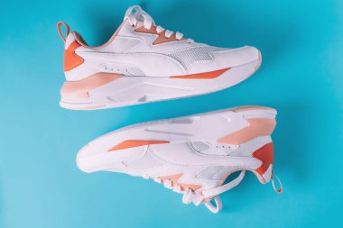 Mavi arka planda mercan desenli beyaz kadın ayakkabıları. Üst Manzara. Düz yatıyordu.