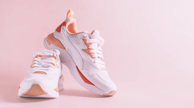 Pembe arka planda mercan desenli beyaz kadın spor ayakkabıları.