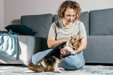 Kıvırcık saçlı, neşeli, çıplak ayaklı, köpek Corgi 'si olan kadın. İtaat eğitimi, evcil hayvan besleme, oturma, dinlenme ve koltuğun yanındaki rahat oturma odasında oynama. Hafta sonu boş zaman aktivitesi