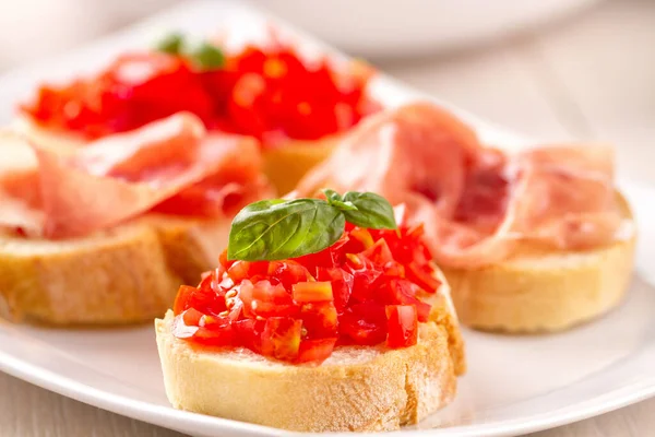 ブルスケッタパルマハムとプレート上の新鮮なトマトとイタリアの前菜ブルスケッタ — ストック写真
