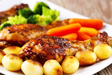 Kızarmış tavuk budu, patates, havuç, brokoli ve Brüksel lahanası.