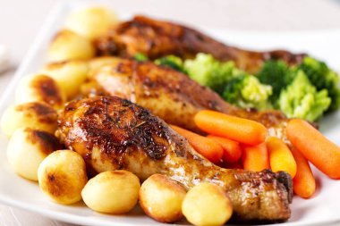 Kızarmış tavuk budu, patates, havuç, brokoli ve Brüksel lahanası.