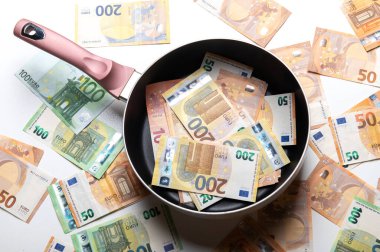 Beyaz arka planda euro banknotları olan yeni kızartma tavası.