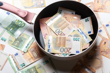 Beyaz arka planda euro banknotları olan yeni kızartma tavası.