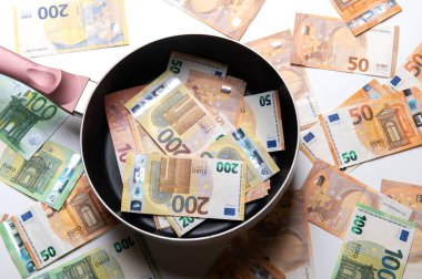 Beyaz arka planda euro banknotları olan yeni kızartma tavası.