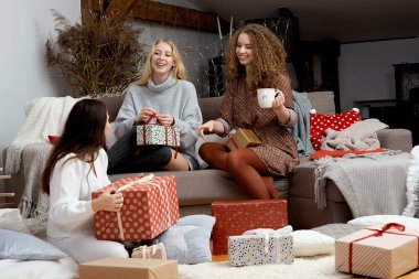 Evde hediye paketlerken eğlenen bir grup kadın, harika bir takım arkadaşı Noel hediyesi paketliyor.