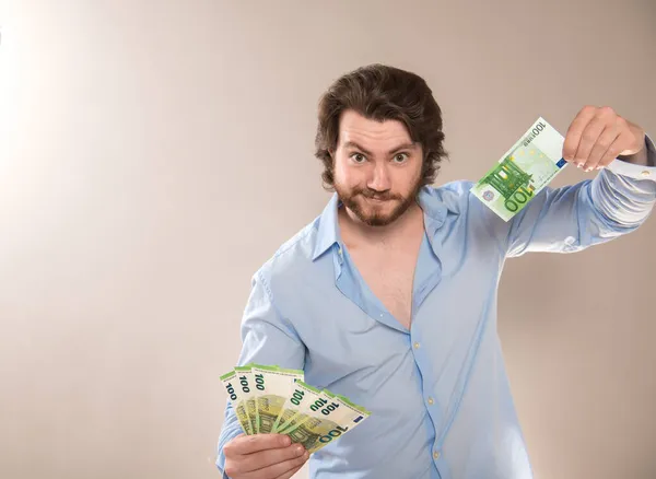 Uçarı zengin bir genç adam elinde 100 Euro 'luk banknotlar tutuyor ve kameraya meydan okuyor.