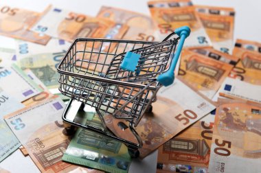Yüzeydeki boş alışveriş arabası çoklu avro banknotlarıyla kaplı.