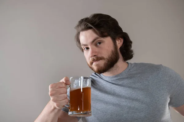 Bira Bardağıyla Sakallı Adam Gri Arka Plandan Kameraya Bakıyor — Stok fotoğraf