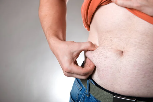 Överviktig Man Vidrör Magen Fett Den Grå Bakgrunden — Stockfoto