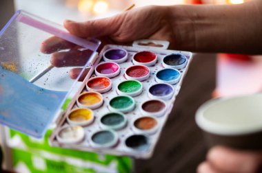 Holding suluboya boya ve fırça doğada resim yaparken erkek fotoğrafı yakın çekim eller.