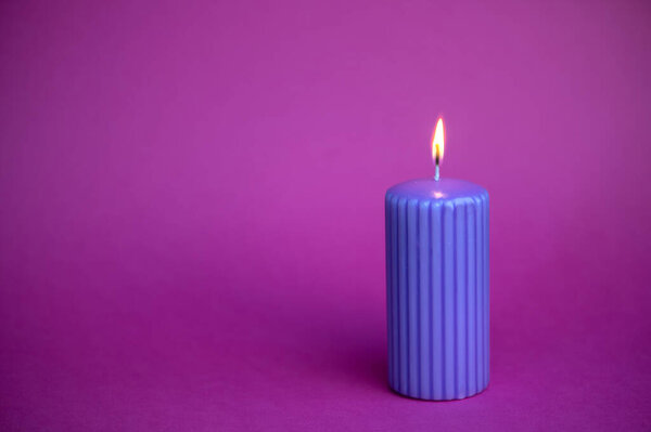 Blue candle with orange flame over purple background