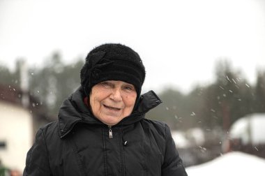 Kameraya bakarak gülümseyen yaşlı bir kadın portresi 