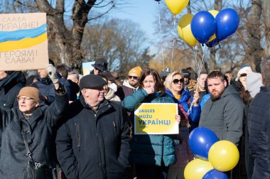 Riga, Letonya - 05 Mart 2022: Ukrayna 'daki savaşı ve Rusya' nın işgalini protesto. Ukrayna 'yı destekleyen ve Putin' in savaşı durdurmasını isteyen gösterilerde bayrakları, işaretleri ve posterleri olan bir kalabalık..