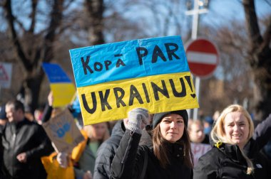 Riga, Letonya - 05 Mart 2022: Ukrayna 'daki savaşı ve Rusya' nın işgalini protesto. Ukrayna 'yı destekleyen ve Putin' in savaşı durdurmasını isteyen gösterilerde bayrakları, işaretleri ve posterleri olan bir kalabalık..