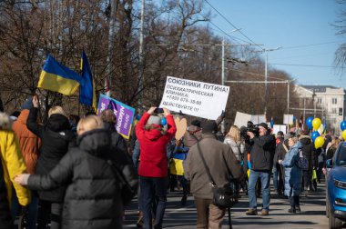 Riga, Letonya - 05 Mart 2022: Ukrayna 'daki savaşı ve Rusya' nın işgalini protesto. Ukrayna 'yı destekleyen ve Putin' in savaşı durdurmasını isteyen gösterilerde bayrakları, işaretleri ve posterleri olan bir kalabalık..