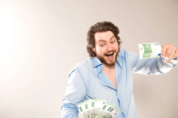 在灰色背景下手里拿着100欧元钞票的快乐的高加索人的画像 — 图库照片