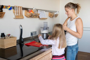 Anne ve küçük kızı ev mutfağında tatlı krema hazırlıyorlar.