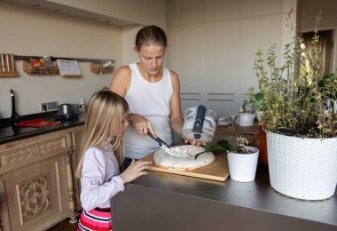 Anne ve kızı evde tatlı tatlı kremalı pasta hazırlıyorlar.