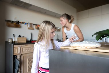 Anne ve kızı evde tatlı tatlı kremalı pasta hazırlıyorlar.