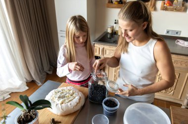 Anne ve kızı evde tatlı tatlı kremalı pasta hazırlıyorlar.