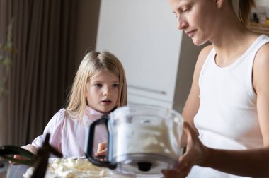Anne ve kızı evde tatlı tatlı kremalı pasta hazırlıyorlar.