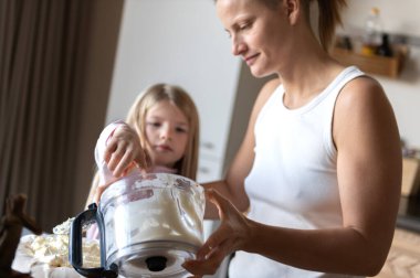 Anne ve kızı evde tatlı tatlı kremalı pasta hazırlıyorlar.