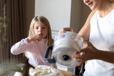 Anne ve kızı evde tatlı tatlı kremalı pasta hazırlıyorlar.