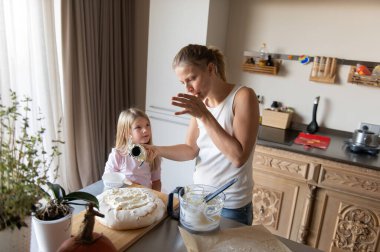 Anne ve kızı evde tatlı tatlı kremalı pasta hazırlıyorlar.