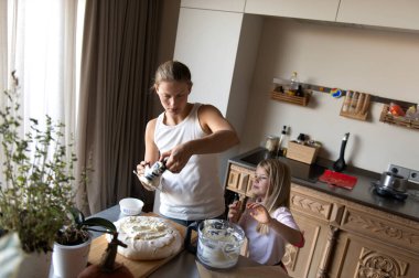 Anne ve kızı evde tatlı tatlı kremalı pasta hazırlıyorlar.