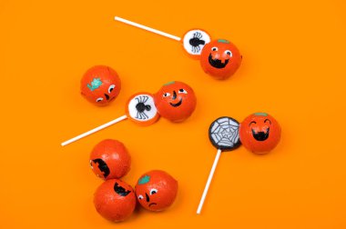 Siyah örümcekli Cadılar Bayramı şekeri, gülümseyen balkabakları ve turuncu arka planda örümcek ağı, üst manzara