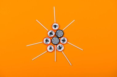 Siyah örümcekli Cadılar Bayramı şekeri ve turuncu arka planda örümcek ağı, üst görünüm