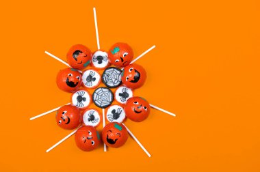 Siyah örümcekli Cadılar Bayramı şekeri, örümcek ağı, gülümseyen ve turuncu arka planda kızgın balkabakları, üst manzara