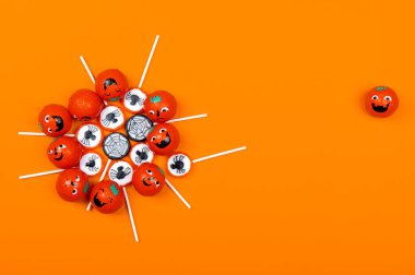 Siyah örümcekli Cadılar Bayramı şekeri, örümcek ağı, gülümseyen ve turuncu arka planda kızgın balkabakları, üst manzara