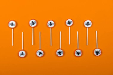 Siyah örümcekli Cadılar Bayramı şeker sırası ve turuncu arka planda örümcek ağı, üst görünüm