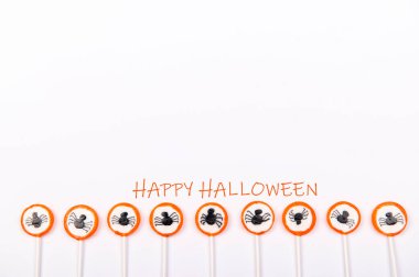 Siyah örümcekli bir sıra şeker ve beyaz arka planda izole edilmiş mutlu Cadılar Bayramı