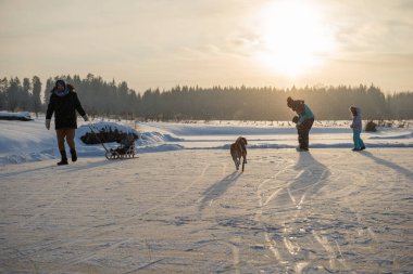 Happy family with three children and dog having fun at ice-skating rink outdoor
