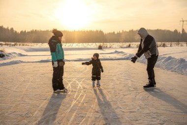 Mutlu aile dışarıda buz pateni pistinde eğleniyor.