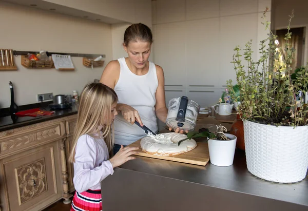 Anne ve kızı evde tatlı tatlı kremalı pasta hazırlıyorlar.