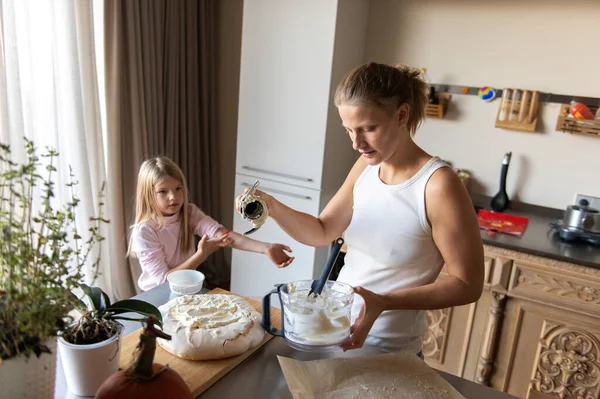 Anne ve kızı evde tatlı tatlı kremalı pasta hazırlıyorlar.