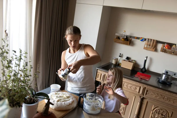 Anne ve kızı evde tatlı tatlı kremalı pasta hazırlıyorlar.