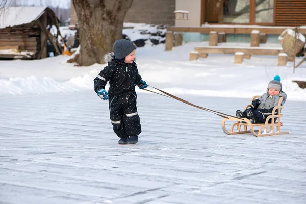 Kış gölünde mutlu çocuklar, kar yağarken kızakla oynuyorlar. Çocukluk mutluluğu kavramı