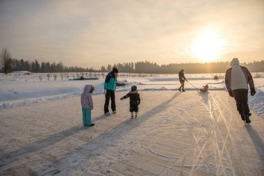 Happy family with three children having fun at ice-skating rink outdoor