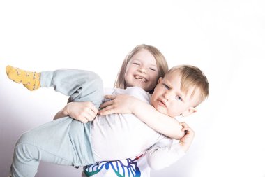 Two happy funny little children-sister are holding their little brother on a white studio background