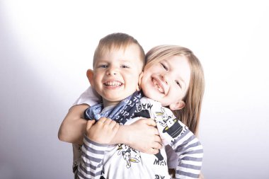 İki küçük mutlu çocuk - kız ve erkek kardeş gülümseyip sarılıyorlar